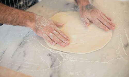 unas manos amasando masa en forma circular sobre una mesa de marmol